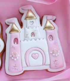 two decorated cookies in the shape of castle and princess's castle on pink paper