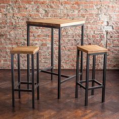 three stools and a table in front of a brick wall with wood flooring