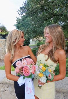 two beautiful young women standing next to each other holding bouquets in their hands and smiling