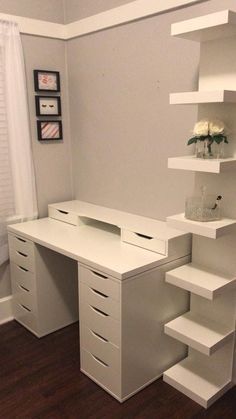 a white desk with drawers and shelves in a small room next to a window on the wall