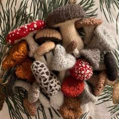 a pile of knitted mushrooms sitting on top of a tablecloth covered in pine needles