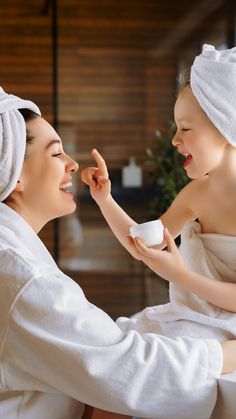 a woman holding a child in her arms while they both have towels on their heads