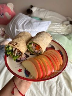 a person holding a plate with an apple and cheese sandwich on it while laying in bed