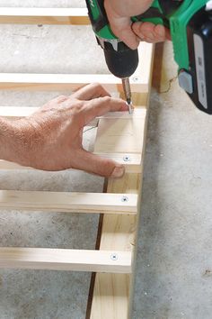 a person using a power drill to attach wood planks on the floor with one hand