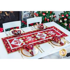 a table set for christmas with red and gold placemats, plates and silverware