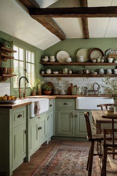 a kitchen filled with lots of green cupboards and counter top space next to a dining room table