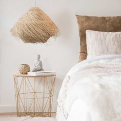 a bedroom with a bed, side table and hanging basket on the wall next to it