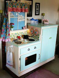 an old fashioned play kitchen with blue cabinets and white stove top oven in the corner