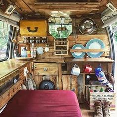 the interior of an old camper with wood paneling and red bedspread