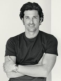 a black and white photo of a man with his arms crossed smiling at the camera