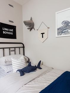 a bed with white sheets and blue pillows in a room that has shark decorations on the wall