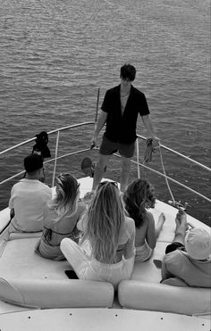 black and white photograph of people sitting on the back of a boat