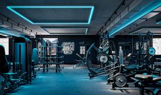 an empty gym with blue lights on the ceiling and machines in the foreground,