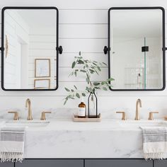 the bathroom is decorated in white and black with gold accents, including two mirrors on the wall