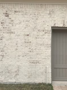 a white brick building with a gray garage door