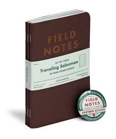 a brown field notes book with a green badge on the front and back cover next to it