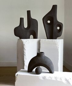 two black sculptures sitting on top of a white block