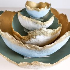 three bowls are stacked on top of each other in gold and green dishes with matching plates