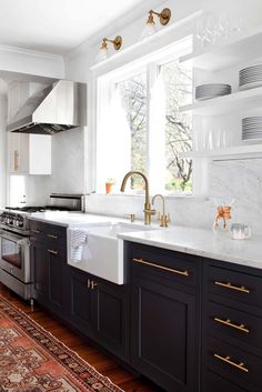 a kitchen with black cabinets and white counter tops, gold pulls on the faucets