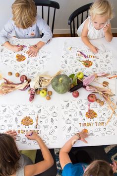 three children sitting at a table with turkey themed thanksgiving coloring pages on it and pumpkins in the background