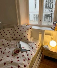 a laptop computer sitting on top of a bed next to pillows and a lamp in a bedroom