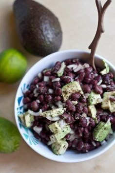 a bowl filled with beans and avocado next to limes