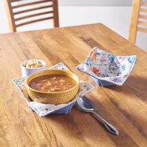 a wooden table topped with two bowls of soup