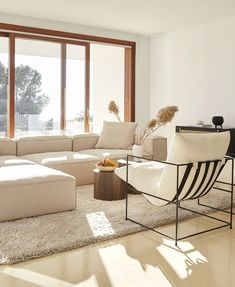 a living room filled with lots of furniture next to a large window covered in sunlight