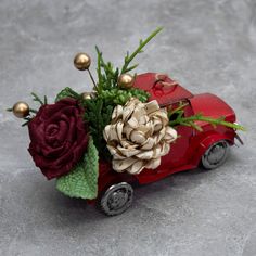 a red toy car with flowers in the front and on the back, sitting on a gray surface