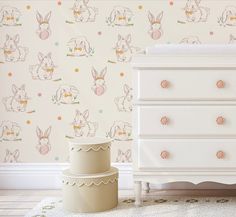 a white dresser sitting next to a wallpaper with bunny rabbits on it's face