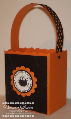 an orange and black shopping bag with a spider on it's front, sitting on a table