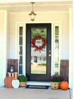 the front door is decorated with pumpkins and wreaths