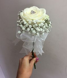 a hand holding a white rose with baby's breath