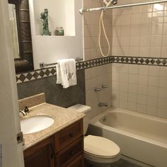 a white toilet sitting next to a bath tub in a bathroom under a mirror above a sink