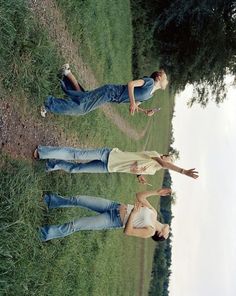 three people standing in the grass with their arms around each other