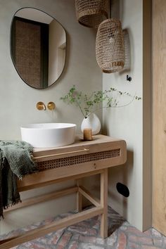 a bathroom with a sink, mirror and vase on the counter next to brick flooring