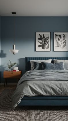 a bedroom with blue walls and grey bedding, two framed pictures on the wall