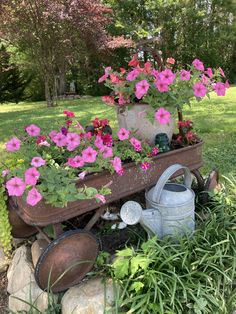 some pink flowers are growing in a pot on a wheelbarrow with watering can