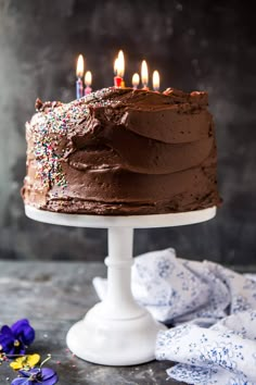 a chocolate cake with lit candles on top and sprinkles around the edges