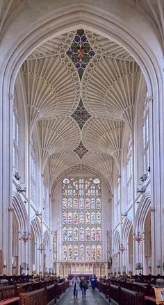 the inside of a large cathedral with stained glass windows and pews on both sides