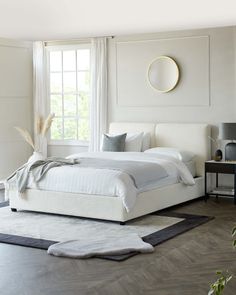 a white bed sitting in a bedroom next to a window