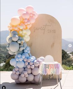 a table topped with balloons next to a wooden sign