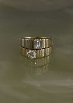 two gold wedding bands with diamonds on them sitting on a surface in front of the camera