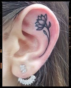 a woman's ear with a flower tattoo on it