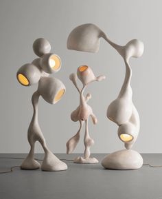 three white sculptures with yellow lights on top of them and one is standing in front of the other