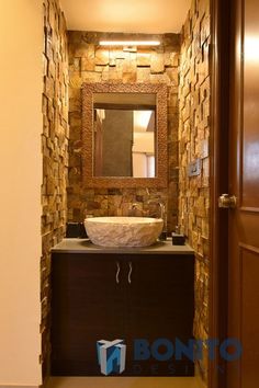 a bathroom sink sitting under a mirror next to a wooden door with a light on it