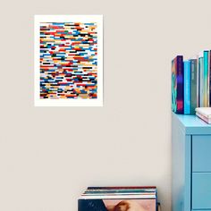 an abstract painting on the wall next to a blue dresser and bookshelf filled with magazines