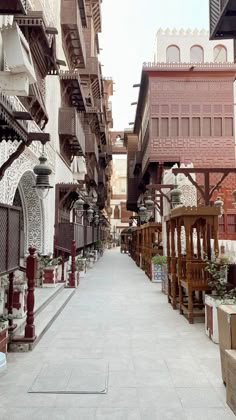 an alley way with lots of wooden benches and planters on the sides, in front of buildings