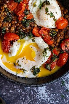 a bowl filled with eggs, tomatoes and other vegetables on top of a gray surface