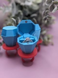 three ring boxes sitting on top of red and blue stands with flowers in the background